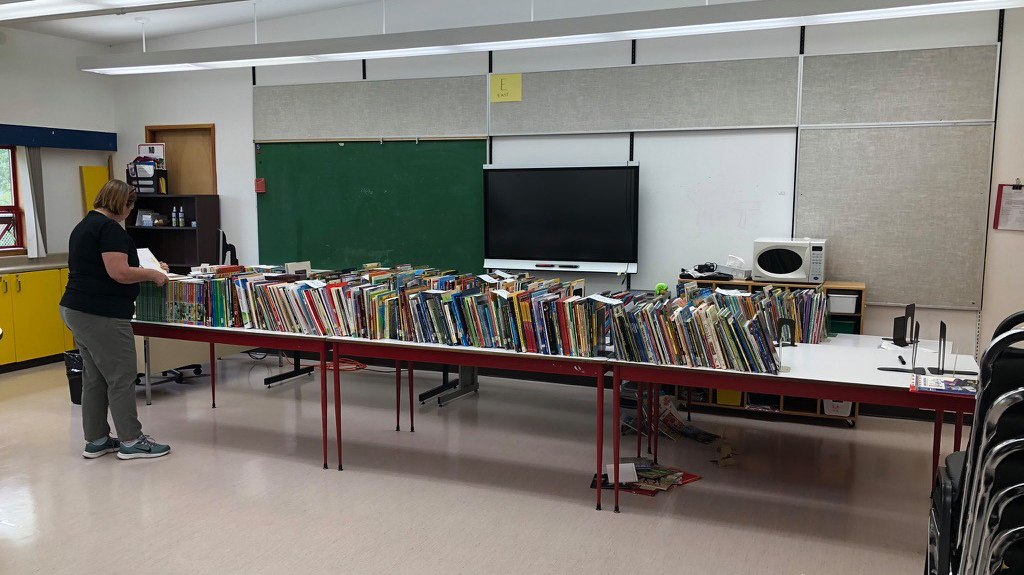 Processing newly arrived books at Gitsegukla library, in a well-lit space that also serves as a classroom.
